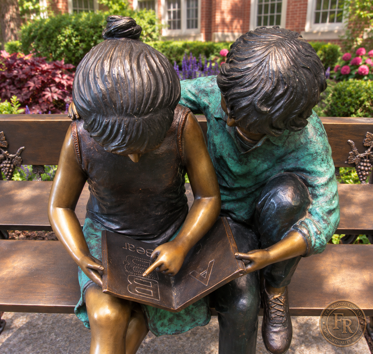 Close school-setting concept of a bronze girl tracing the open book beside a boy with green-patina clothing.
