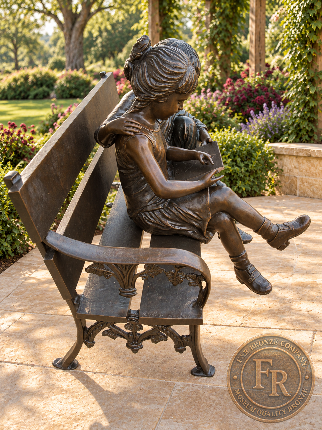 Side garden concept of the two kids reading bronze bench sculpture, showing the curved backrest and seated figures in brown patina.
