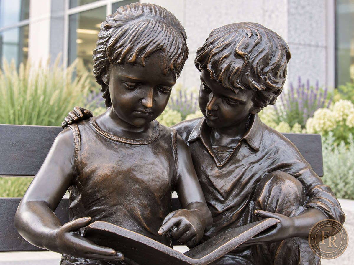 Architectural concept close-up of the two kids reading bronze statue in all-brown patina outside a public library.