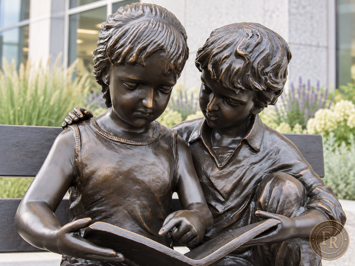 Architectural concept close-up of the two kids reading bronze statue in all-brown patina outside a public library.