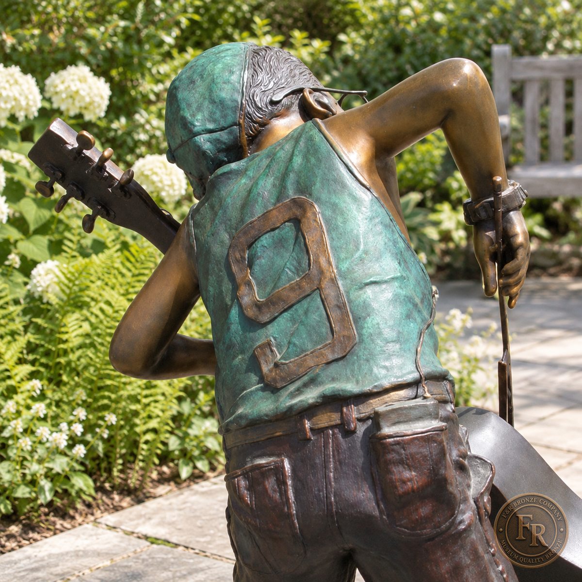 Jumbo Boy Playing Guitar Bronze Statue, item 806, rear detail, in a modest garden setting. Placement concept based on the owner-supplied product photograph.