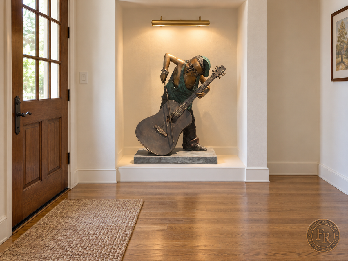 Boy musician bronze sculpture, front three-quarter view, placed in a lit recessed entry alcove with its original base and clear walking space.