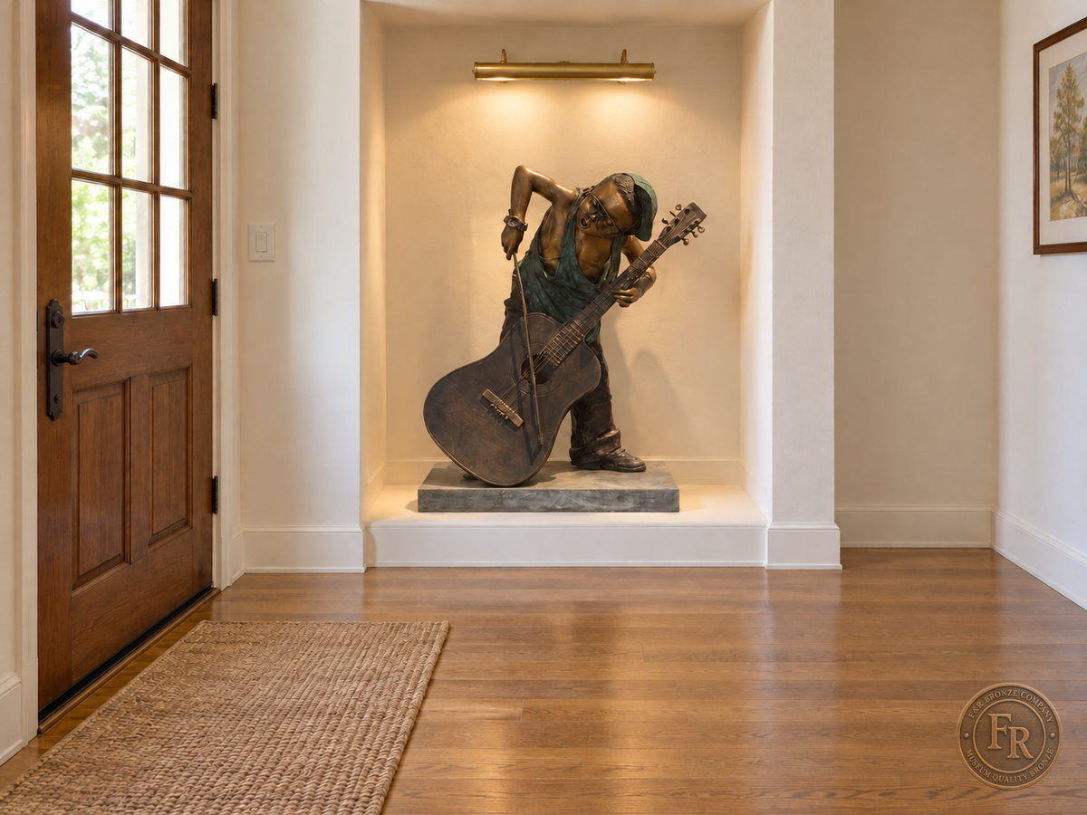 Boy musician bronze sculpture, alternate front view, placed in a lit recessed entry alcove with its original base and clear walking space.