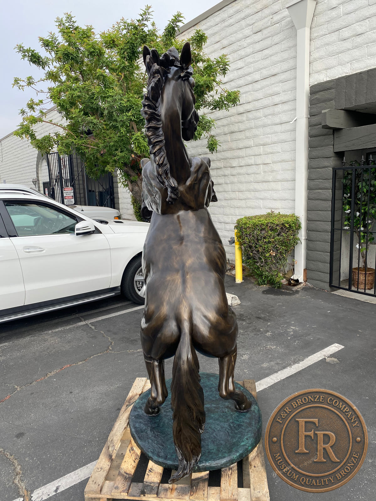 Rear product view of the Left rearing horse bronze sculpture, showing the tail and textured oval base.