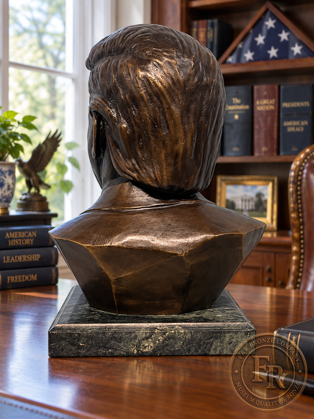 Rear view of the Donald J. Trump bronze bust, showing the sculpted hair and jacket above its dark stone base.