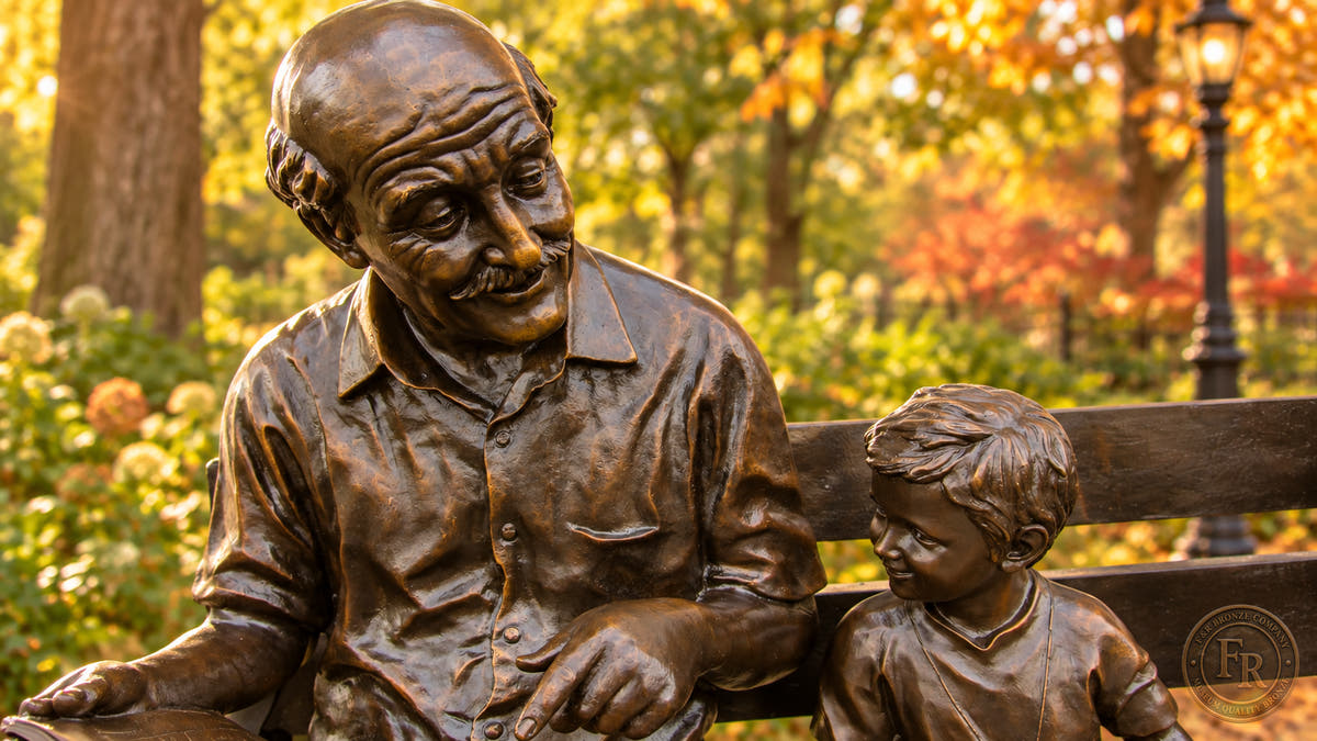 Grandfather and grandson detail of the bronze bench statue, showing the newspaper, child and traditional brown patina.